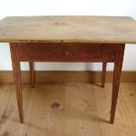 This Birch and pine tap table has a rectangular one-board scrubbed top with breadboard ends set on a plain apron with drawer of dovetailed construction. The apron and gracefully taperedlegs are joined by mortise, tenon and peg; and are in the original red paint.    Height 27" - Width 44" - Depth 27